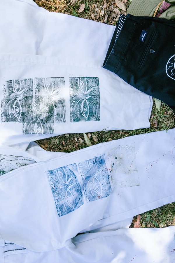 Block-printed white tees and dark pants laid out on grass, showing print variations